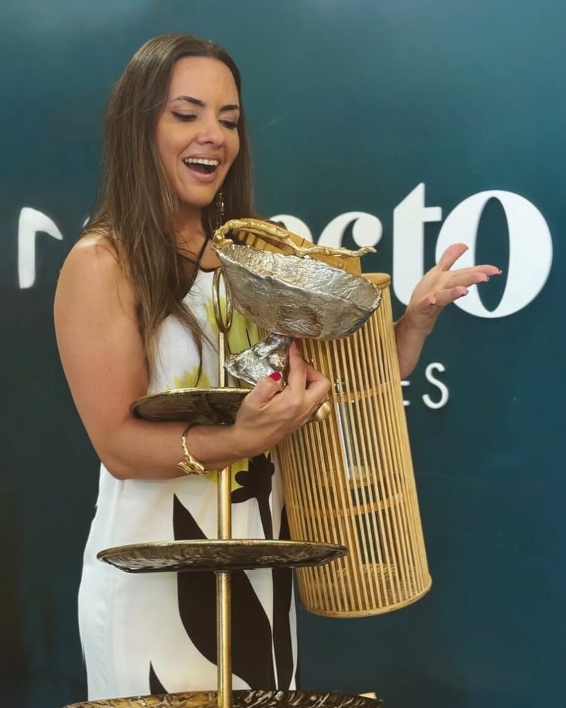 Fundadora da Selecto segurando peças douradas do acervo