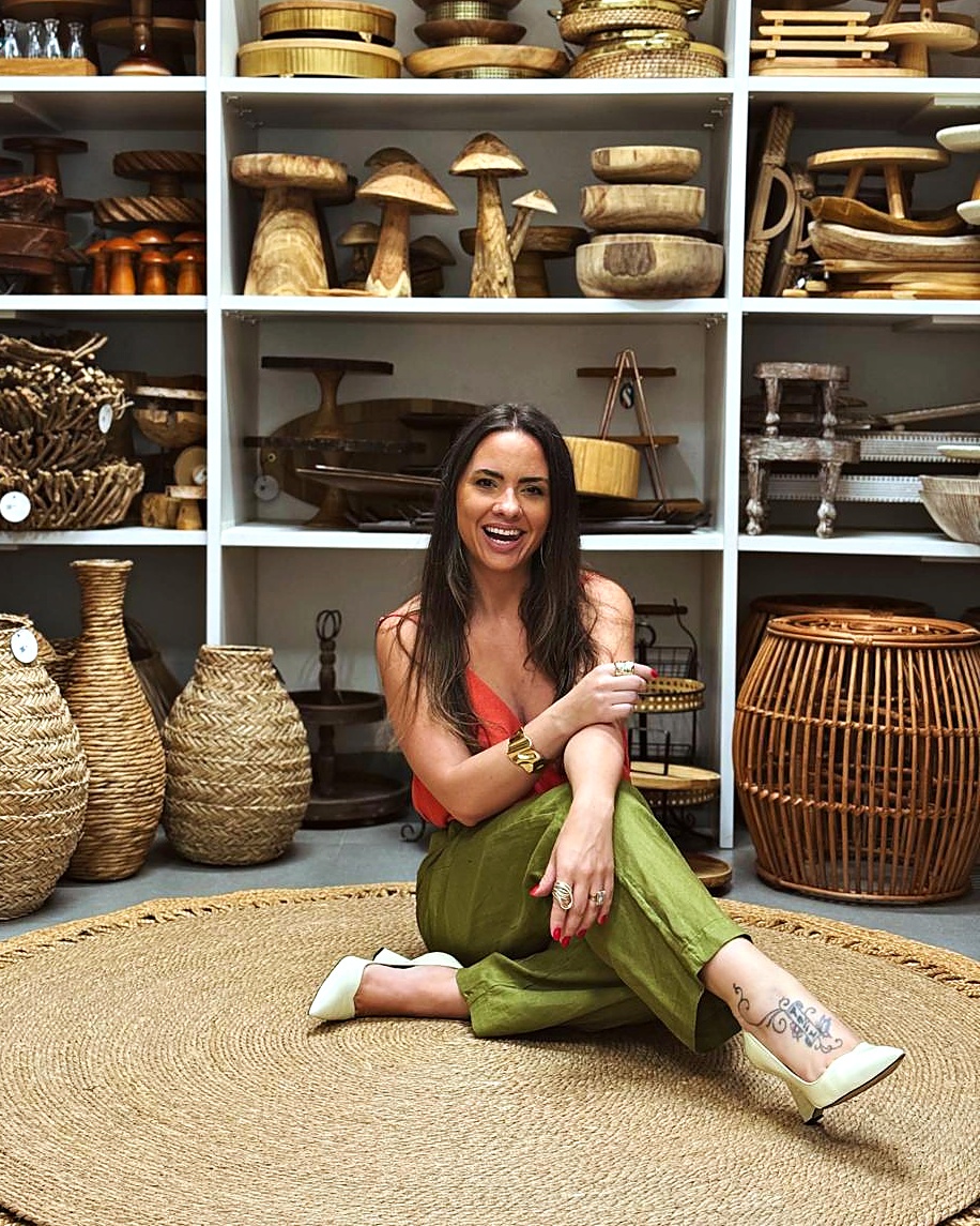 Alinie Araujo, fundadora da Selecto Locações, sentada sobre tapete de fibra natural no showroom