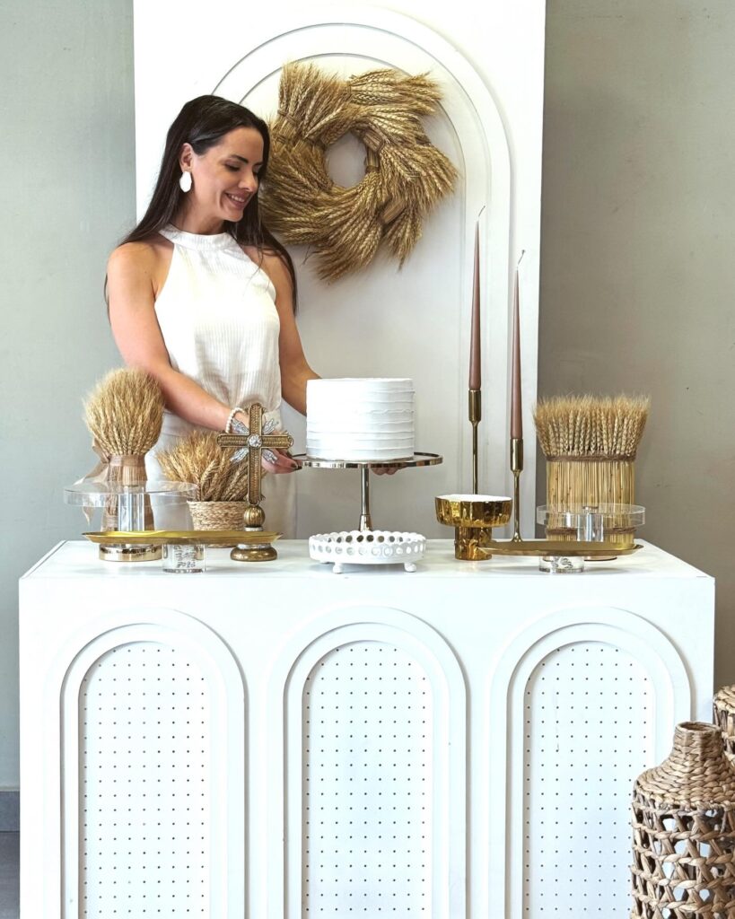 Mulher montando composição de bolo e peças douradas no showroom