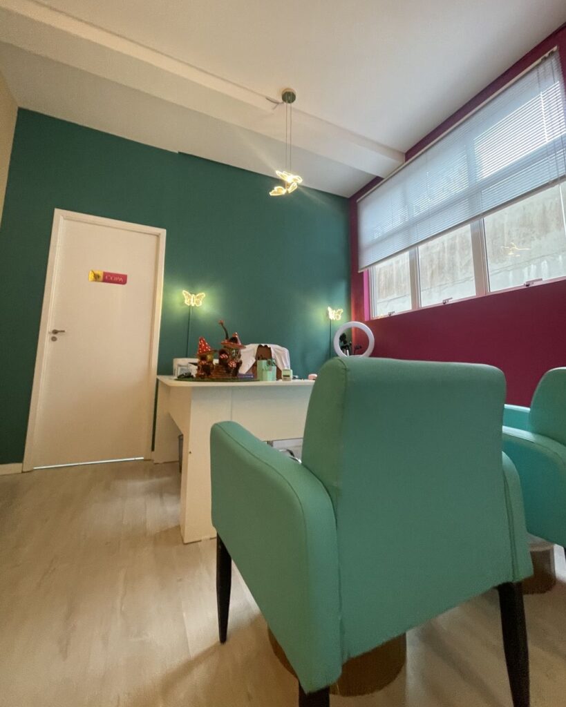Sala de espera da Kolmeeia com poltronas verdes e parede em verde e vinho