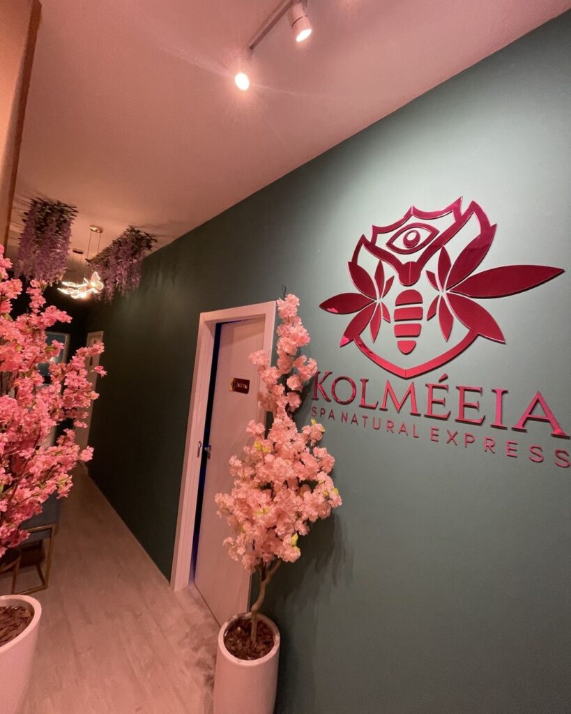 Parede com a marca Kolmeeia e arranjos de flores no espaco em Joinville
