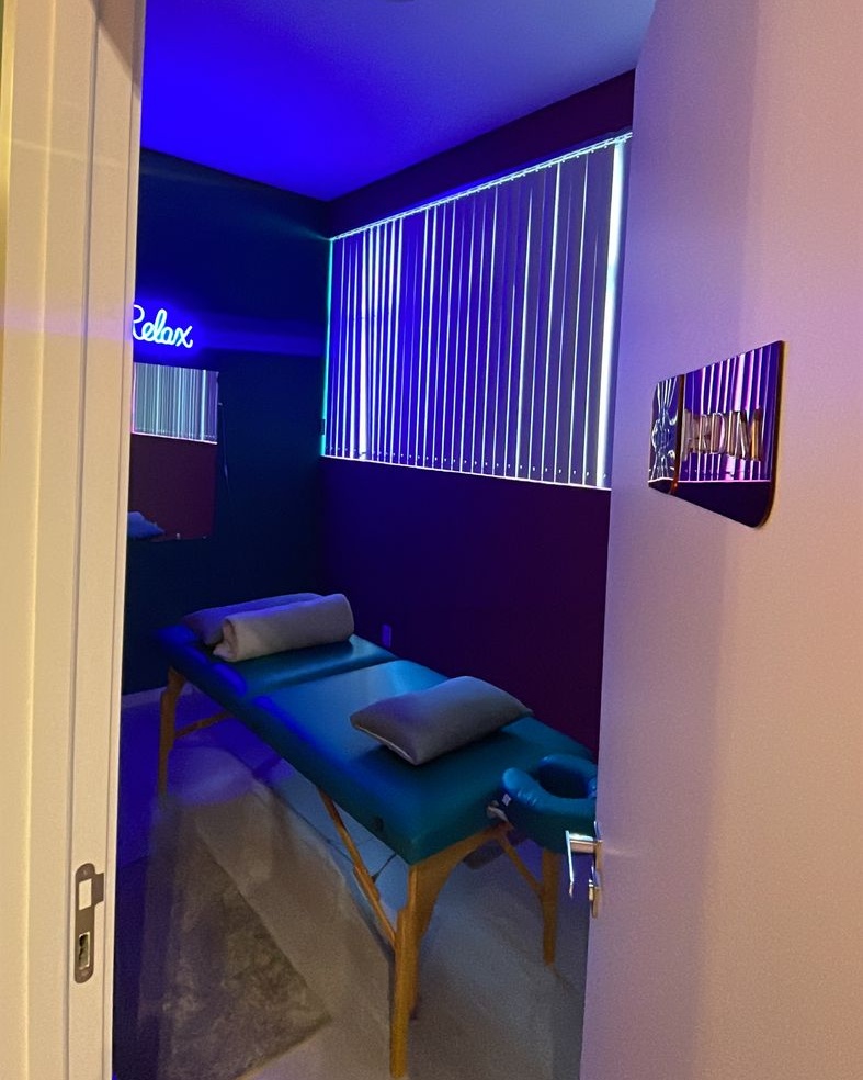 Sala sensorial da Kolmeeia com iluminacao azul e roxa e maca ao centro