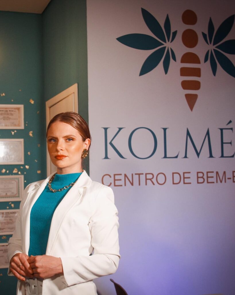 Kerline Sgrott diante da parede com a marca Kolmeeia, centro de bem-estar em Joinville